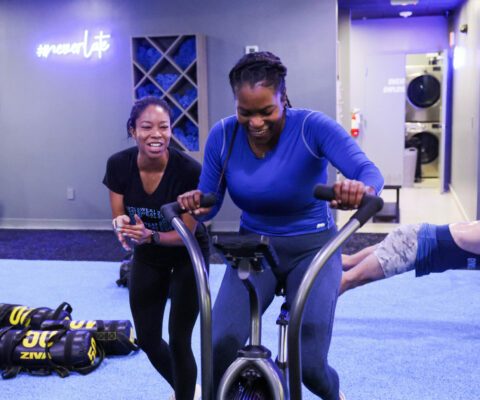 One woman working out with a coach motiving her to complete the exercise